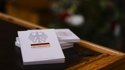 Vier Bücher mit dem Grundgesetz liegen während einer Einbürgerungsfeier auf einem Tisch im Ratssaal des Kieler Rathauses. 