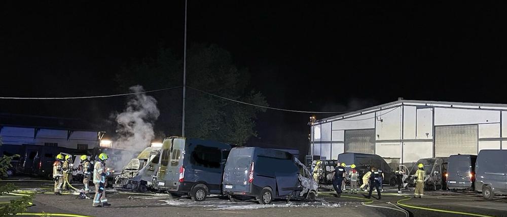 Einsatzkräfte der Berliner Feuerwehr löschen brennende Amazon-Transporter auf einem Grundstück im Ortsteil Wittenau.