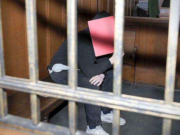 Der Angeklagte Matthieu K. sitzt im Kriminalgericht Moabit in Berlin auf der Anklagebank und verdeckt sein Gesicht mit einer Akte.