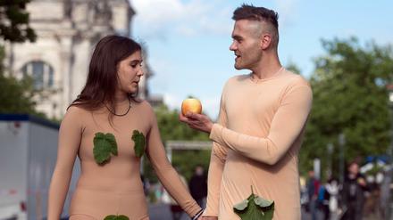 Zwei als Adam und Eva kostümierte Teilnehmer gehen am 24.05.2017 in Berlin am Rande des Eröffnungsgottesdienstes des 36. Evangelischen Kirchentages auf der Straße neben dem Reichstag entlang.
