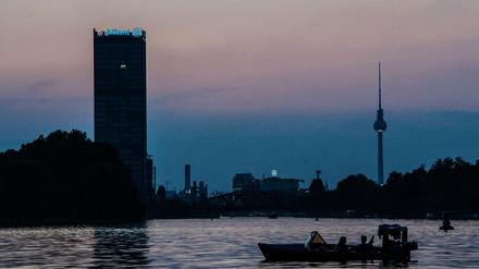 Ein Motorboot fährt abends auf der Spree. Im Hintergrund sind Allianz-Tower und der Fernsehturm zu sehen.