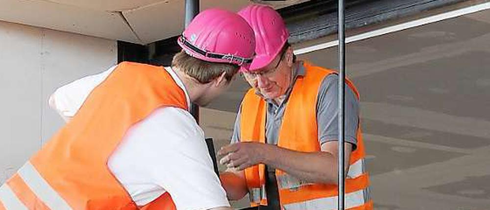 Bauarbeiter montieren in der Haupthalle des künftigen Hauptstadtflughafens einen Monitor.