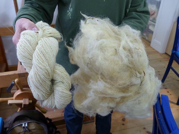 Ein Büschel frisch geschorene Schafwolle und gesponnenes Garn. 
