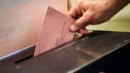 Ein Wähler wirft seinen ausgefüllten Wahlzettel für die Bundestagswahl in Berlin in eine Wahlurne.