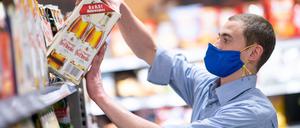 Ein Supermarkt-Mitarbeiter trägt beim Einräumen von Ware einen Mundschutz.