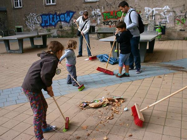 Kinder fegen den Schulhof der Schule am Falkplatz in Prenzlauer Berg.