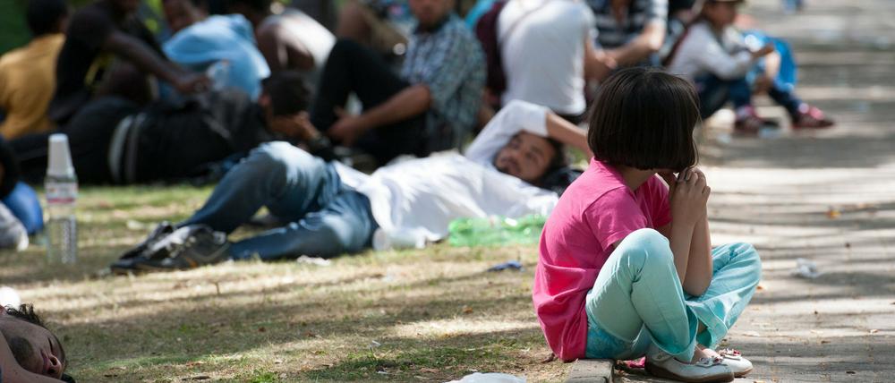 Ein Flüchtlingskind sitzt in Berlin auf dem Gelände des Landesamtes für Gesundheit und Soziales (LaGeSo) auf einem Bordstein. Auch die Helfer sind langsam am Ende ihrer Kräfte.