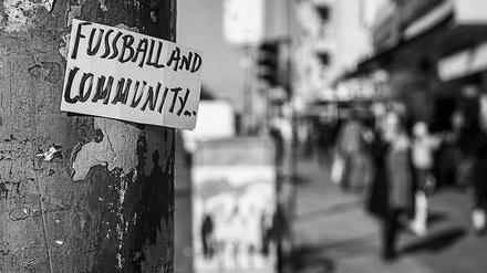 "Fussball and Community" - zweisprachiger Laternensticker im Berliner Straßenbild.