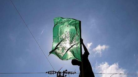 Ein militantes Mitglied des militärischen Flügels der palästinensischen Hamas hält im Gaza-Streifen eine Hamas-Fahne hoch.