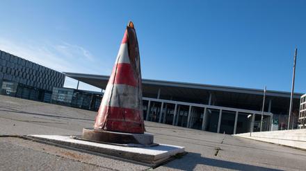 Ein Warnkegel steht vor dem Terminal des Hauptstadtflughafens BER. Die Verzögerungen auf der Baustelle des BER haben weitere finanzielle Konsequenzen: Nach Presseberichten wird für die Inbetriebnahme und den Ausbau des Flughafens ein weiterer Nachschlag von bis zu einer Milliarde Euro benötigt.