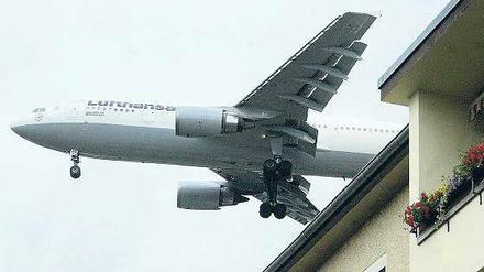 Flugzeug fliegt knapp über einem Haus in der Einflugschneise vom Flughafen Tegel.