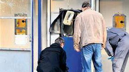 Gesprengt. Ermittler begutachten den beschädigten Geldautomaten. Foto: dpa