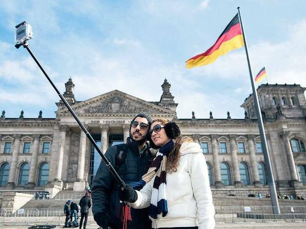 Bitte recht freundlich. Gerade Urlauber verwenden häufig Selfie-Sticks, mit denen sich größere Bildausschnitte ablichten lassen. Auch vor dem Bundestag werden sie häufig gezückt.