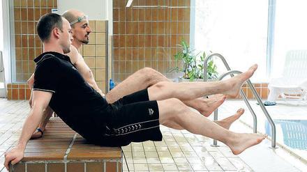 Trockenübung. Schwimmtrainer Alexander Steinhart zeigt Redakteur Björn Seeling den richtigen Beinschlag. 