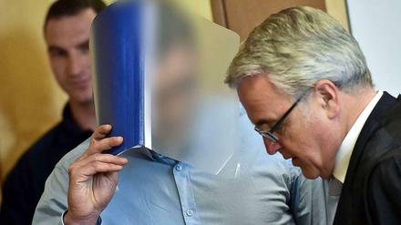 Der Angeklagte Mario K. verdeckt mit einem Hefter sein Gesicht neben seinem Anwalt Axel Weimann am Landgericht in Frankfurt (Oder).