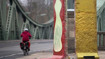 Originalteile der ehemaligen Berliner Mauer stehen in Potsdam (Brandenburg) vor der Kulisse der historischen Glienicker Brücke. 