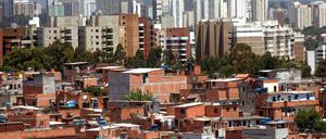 Vorne eine "planlose" Favela, hinten Hochhäuser in Sao Paulo. Können Wohngebiete nach den Regeln einer Favela besser geplant werden?
