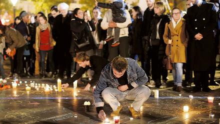 Menschen entzünden auf dem Platz der Republik in Paris Kerzen. Auch in privaten Wohnungen sollten Kerzen brennen, findet Tagesspiegel-Leserin Renate G., als verbindendes Zeichen.