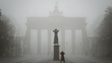 Eine Passantin fotografiert im Nebel das Brandenburger Tor. 