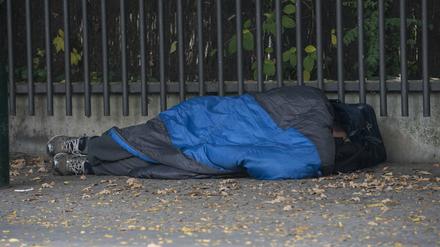 Ein Obdachloser liegt in einem Schlafsack gehüllt unter einem Dachvorsprung vor dem Berliner Zoo.