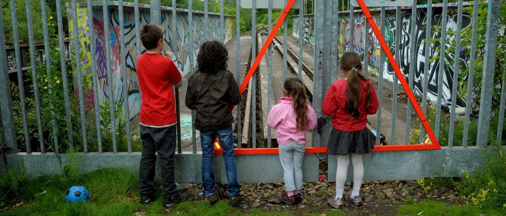 Kinder schauen durch einen Gitterzaun beim Park am Gleisdreieck.