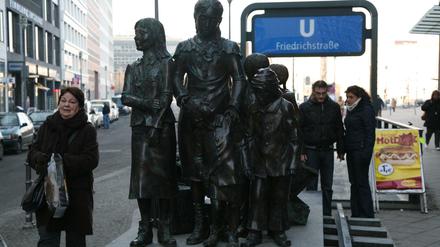 Passanten betrachten die Figurengruppe " Züge in das Leben- Züge in den Tod " vom Frank Meisler am Bahnhof Friedrichstraße in Berlin-Mitte.