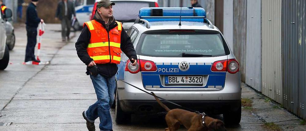 Ein Polizist untersucht mit einem Spürhund den Fundort der Babyleiche. 