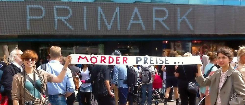 Zwei Frauen halten ein Banner mit der Aufschrift "Mörderpreise" vor der neuen Filiale in die Höhe.