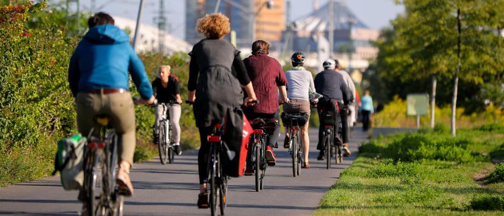 Zahlreiche Radfahrer fahren in Berlin im Sonnenschein durch den Park am Gleisdreieck in Richtung Potsdamer Platz.