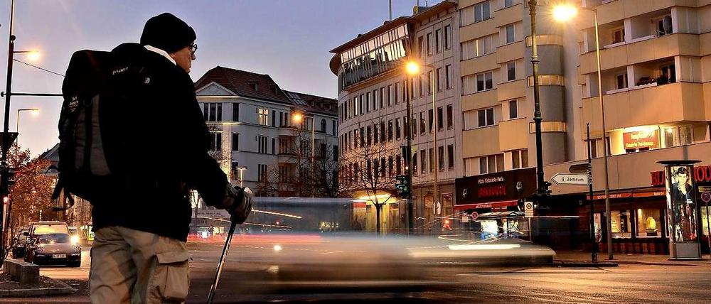 Unser Autor Helmut Schümann steht in der Morgendämmerung mit Rucksack an einer Straße in Berlin.