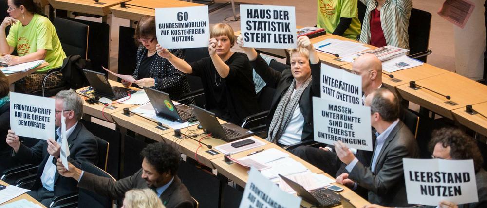 Abgeordnete der Grünen hielten während der Aktuellen Stunde zur Flüchtlingssituation Schilder zum Protest gegen die vom Senat geplante Randbebauung des Tempelhofer Feldes hoch.