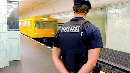Ein Polizist steht vor einem Bahngleis.