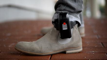 Ein Mitarbeiter der IT-Stelle der hessischen Justiz veranschaulicht am 11.01.2017 in Bad Vilbel (Hessen), wie eine elekronische Fußfessel getragen wird. Islamistische Gefährder sollen künftig mit elektronischen Fußfesseln überwacht werden können. Bildfunk+++