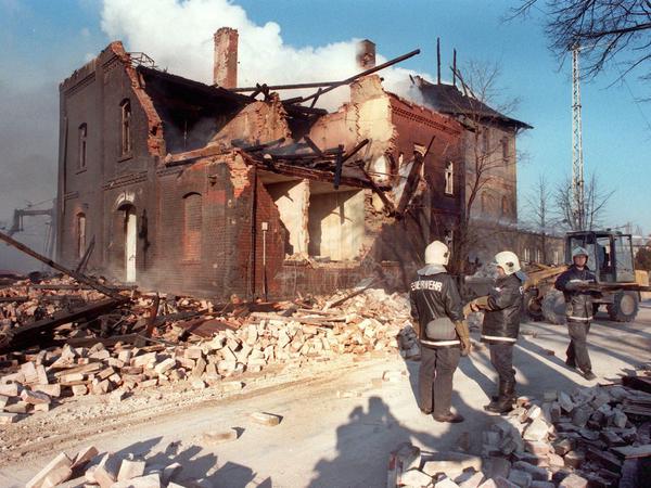 Feuerwehrleute stehen am 20.11.1997 neben dem völlig zerstörten Bahnhofsgebäude von Elsterwerda.