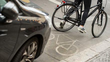 Eine Radfahrerin umfährt in Berlin ein auf dem Radweg stehendes Auto