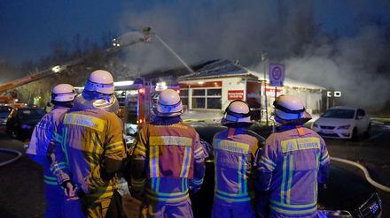 Feuerwehrmänner vor dem ausgebrannten Supermarkt in Treptow.