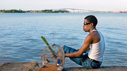 Ein Bewohner von Paramaribo mit seinem Vogel am Fluss Suriname.