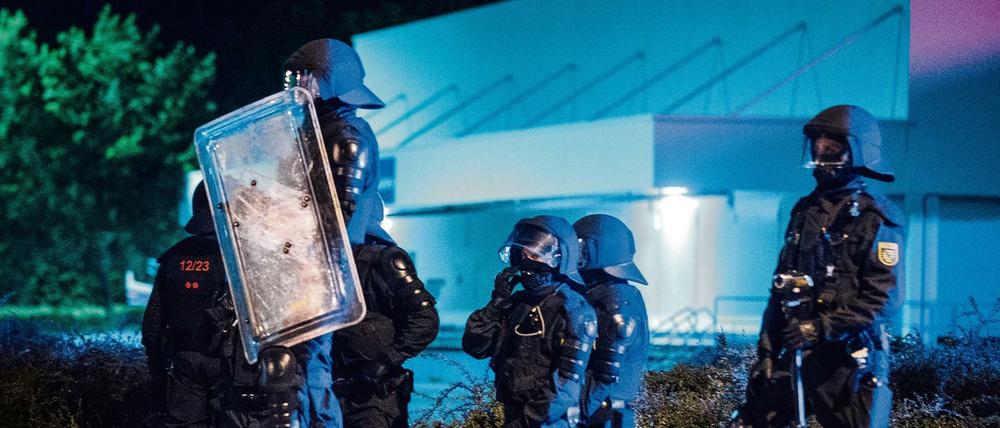 Polizisten stehen am Abend des 23.08.2015 vor dem ehemaligen Praktiker-Baumarkt in Heidenau (Sachsen) auf der Straße. Bei Protesten von Anwohnern und Rechtsextremen gegen eine neue Flüchtlingsunterkunft war es hier zu Ausschreitungen gekommen.