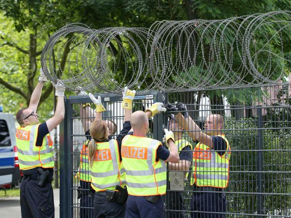 Polizisten montieren in Hamburg Rollen mit Stacheldraht auf einen Zaun am Bahnhof Sternschanze, nahe dem Messegelände. Der G20-Gipfel findet am 07. und 08. Juli statt.