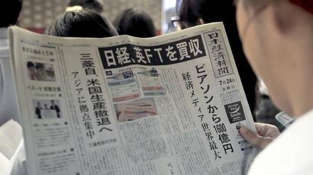 Aufregende Lektüre. Ein Mann in einem Tokioter Bahnhof liest in der „Nikkei“-Ausgabe vom 24. Juli den Aufmacher über den Kauf der britischen „Financial Times“. 