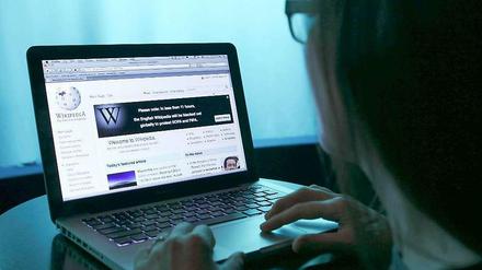 Frau tippt auf Laptop, auf dem Wikipedia geöffnet ist