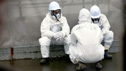 Krebsvorsorge am Reaktor: Eingehüllt in Schutzkleidung, machen Männer eine Pause von den Aufräumarbeiten am Kraftwerk in Fukushima.