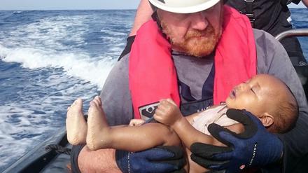 Ein deutscher Retter der Organisation Sea-Watch hält ein ertrunkenes Flüchtlingsbaby in den Armen.