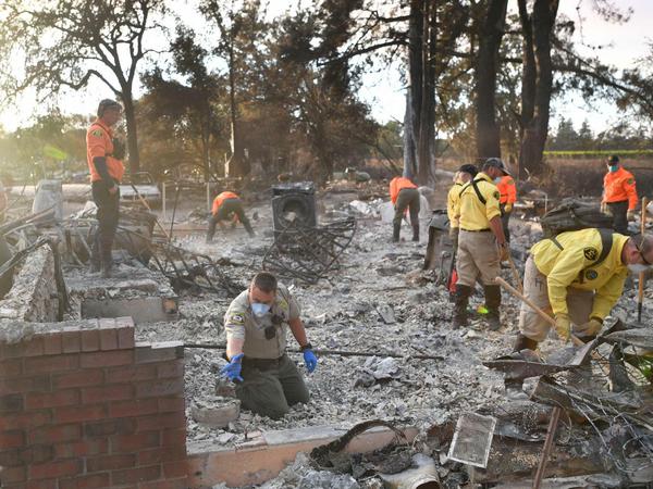 Einsatzkräfte suchen in einem abgebrannten Haus nach Leichen.