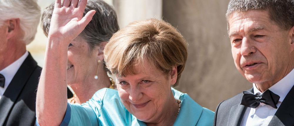 Bundeskanzlerin Angela Merkel (CDU) winkt neben Ehemann Joachim Sauer vor der Eröffnung der 104. Bayreuther Festspiele in Bayreuth.