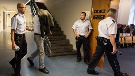 Der Angeklagte (2.vl) kommt am Dienstag mit einer Jacke über dem Kopf von Wachtmeistern begleitet ins Landgericht in Freiburg. Dem 33 Jahren alten Stiefvater wird vorgeworfen, den dreijährigen Alessio im Januar 2015 auf einem Bauernhof in Lenzkirch zu Tode geprügelt zu haben.