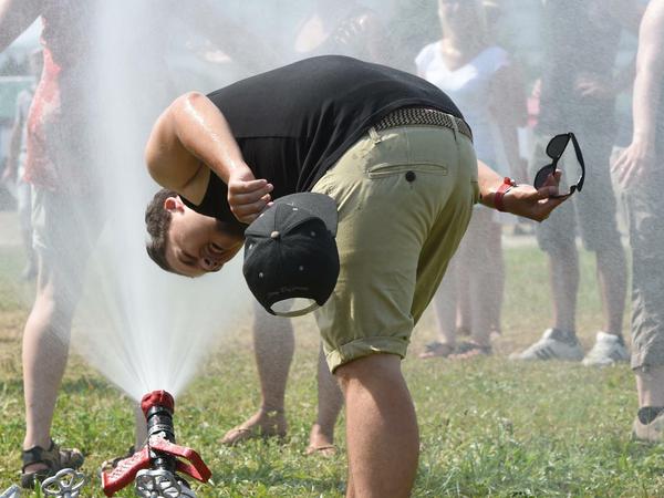 Ein Festivalbesucher duscht sich beim Konzernfestival des Automobilzulieferers ZF in Friedrichshafen (Baden-Württemberg) den Kopf ab. Wegen der großen Hitze hatte die Feuerwehr eine Wasserdusche aufgestellt.