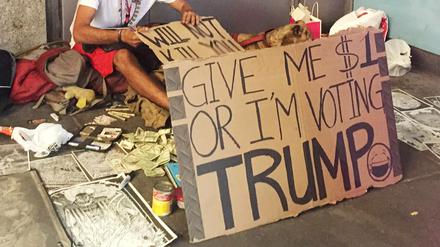 Ein Bettler in New York mit einem Schild mit der Aufschrift "Give me $1 or I'm voting Trump!" (Gib mir 1 Dollar oder ich stimme für Trump) aufgestellt.