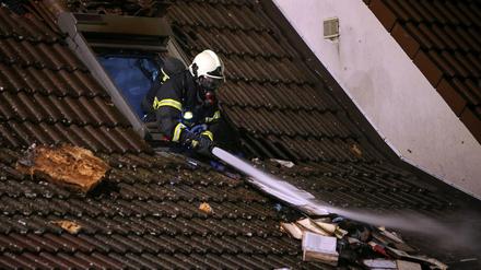Ein Feuerwehrmann löscht am Mittwoch den Brand in einem Haus in Langen (Hessen). Während einer Feier von sechs Jugendlichen ist in dem Einfamilienhaus ein Feuer ausgebrochen. Die Eltern seien laut Polizei zum Zeitpunkt des Brandes nicht zu Hause gewesen.