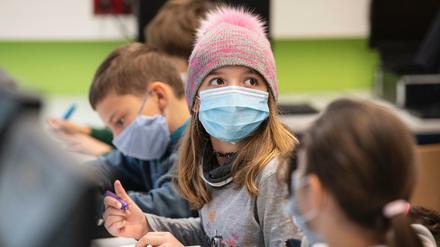 Mit Mundschutzmasken sitzen Schülerinnen und Schüler der fünften Klasse eines Gymnasiums in Frankfurt am Main im Unterricht. 